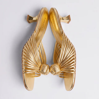 Larroudé gold leather heeled sandals with knotted straps and sculptural heels displayed against a white background.