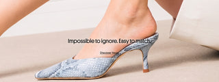 Model's crossed legs wearing a pointed-toe kitten-heel mule in blue-gray snakeskin-textured leather. Banner text: 'Impossible to ignore. Easy to match.