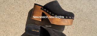Black Larroudé platform mules with wooden heels and floral stud detailing photographed on a concrete surface, with “New season, new heights.”