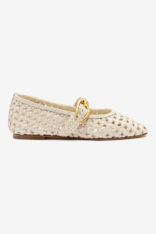An ivory-colored flat shoe with macrame detailing and a heart-shaped buckle on the ankle strap, featuring a closed round toe and golden hardware.