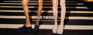 Two women wearing new-season Larroudé shoes and fall looks while standing on a city crosswalk at night.