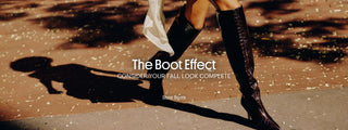 Woman wearing black croc-embossed Larroudé knee-high boots with a fall outfit on a sunlit city street.